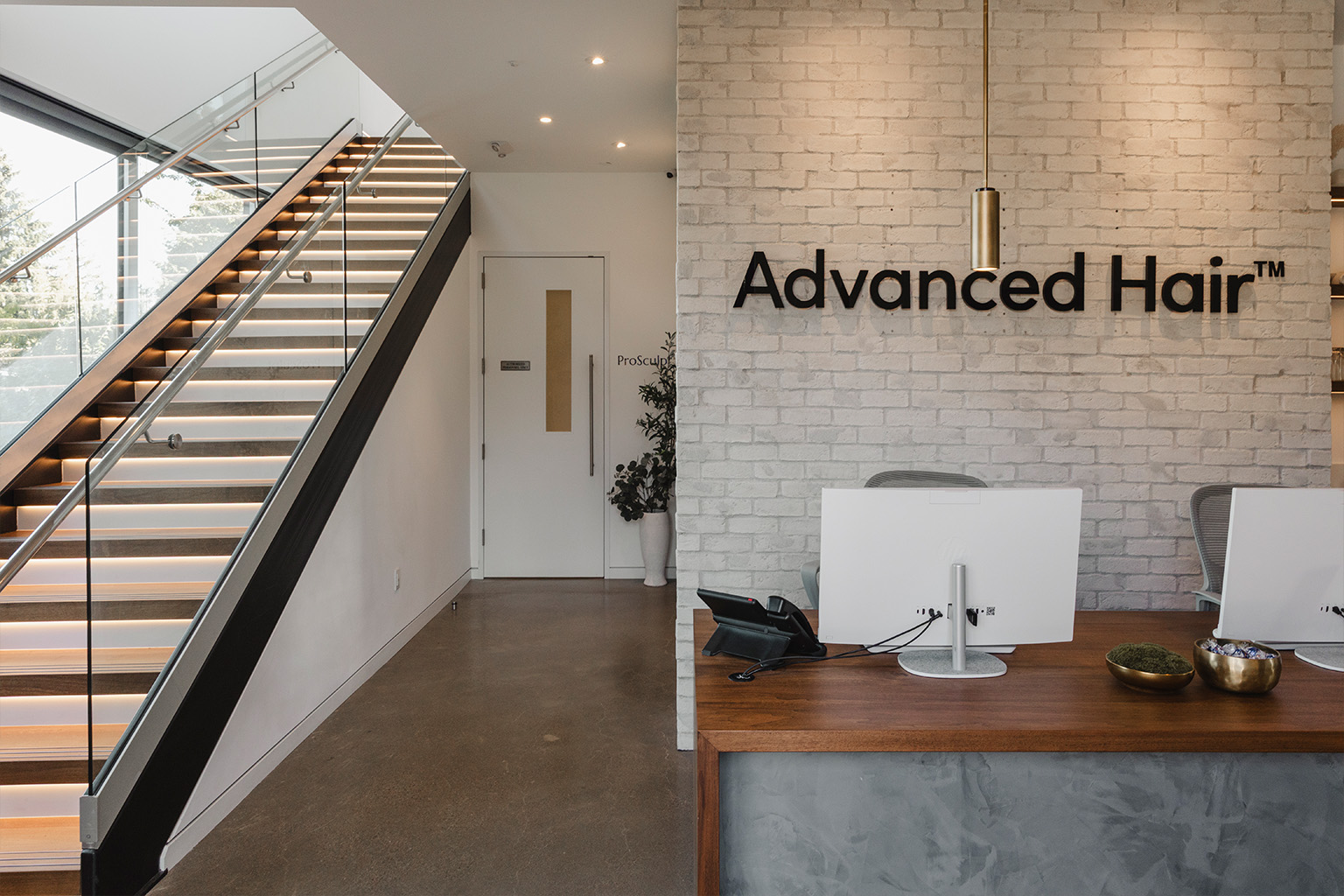 The Advanced Hair reception: a marble desk under backlit signage, with armchairs by a full-height window