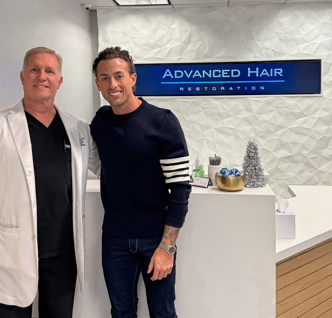 A patient and a clinician standing together at the Advanced Hair Restoration reception desk