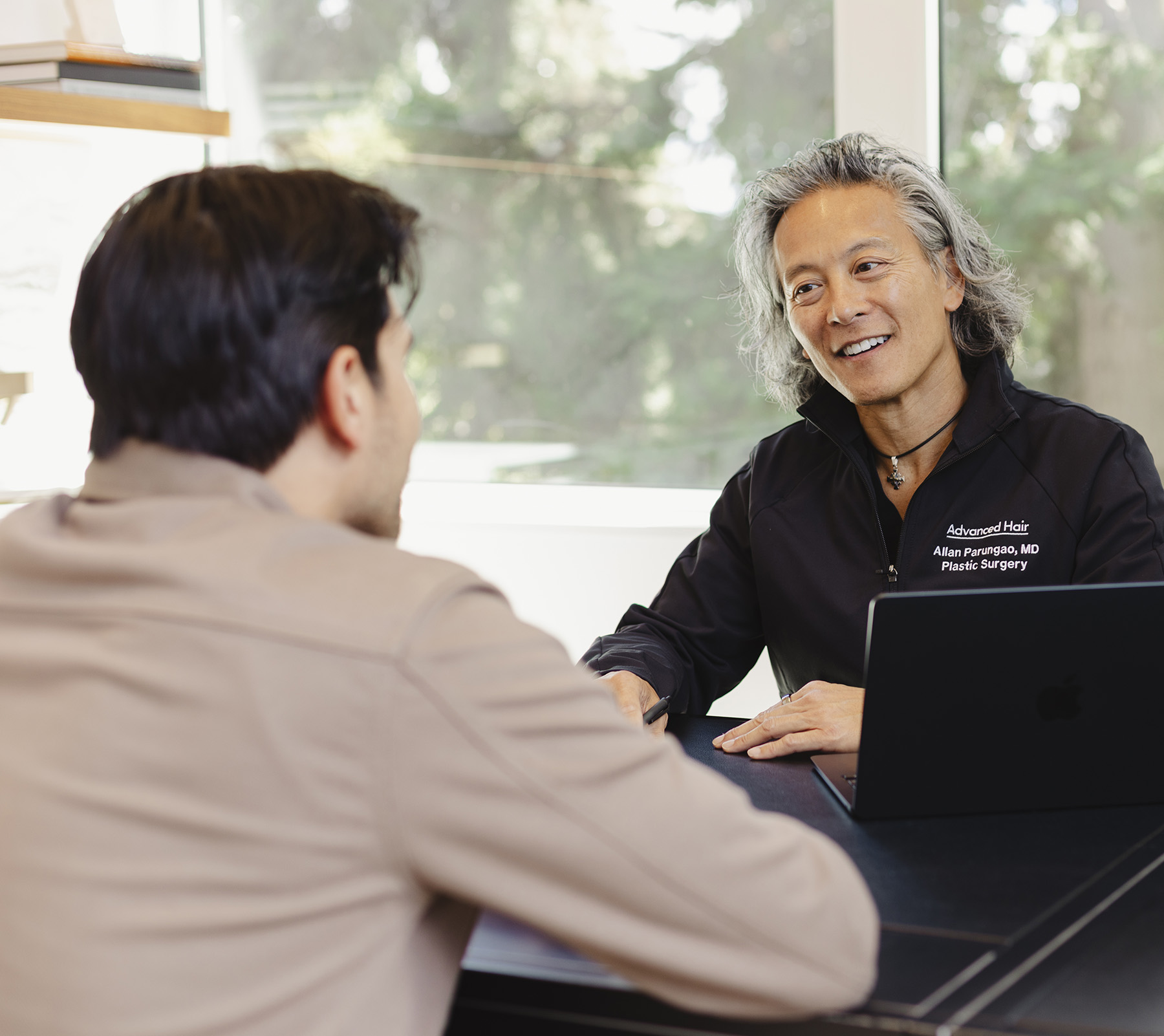 A specialist and a patient talking across a desk during a consultation