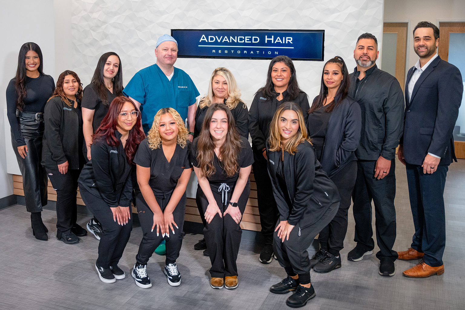 The Advanced Hair Restoration team photographed together beneath their clinic signage